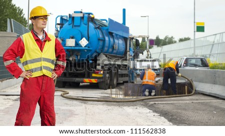 Civil engineer posing in front of road works, where a concrete foundation is poured into the foundation of the road