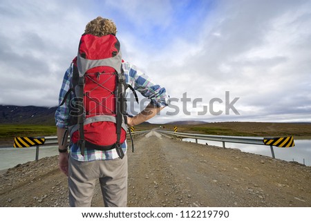 Tired Hiker , with a defeated pose, looks across a bridge at the bus home, leaving from the middle of nowhere.