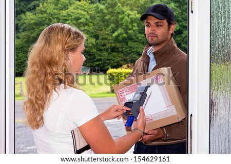 Young woman pays her cash on delivery parcel to a delivery postal worker using a portable, wireless ATM