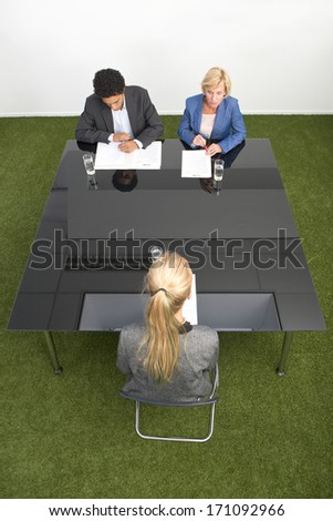 Applicant sitting across a black, glass, conference table with two senior human resource managers during a job interview