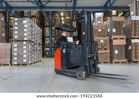 Reach truck driving around cardboard boxes in a warehouse.