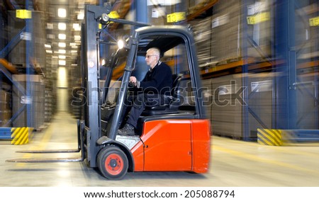 Forklift in a warehouse, driving at speed past the aisles of storage racks