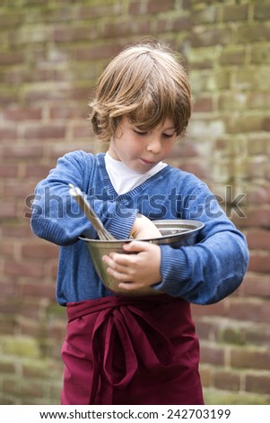 Boy with a sweet tooth, muncing the left overs from batter  in a bowl he's holding Imagine de stoc © 