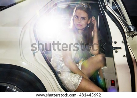 Pretty woman in the door opening of a limousine, ready to get out, and mingle in the nightlife. Bright lights from behind Foto stock © 
