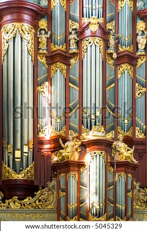 A close up of a church organ with pipes in various sizes, lit by the bright light coming through the church windows.