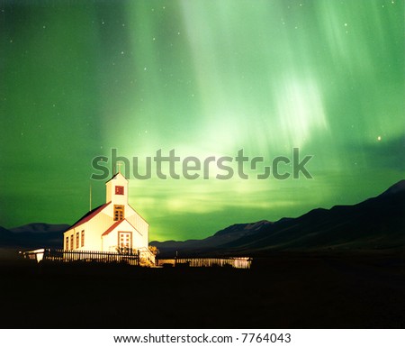 An illuminated church with the magnificent Aurora Borealis, or Northern Light lighting up the sky in Iceland