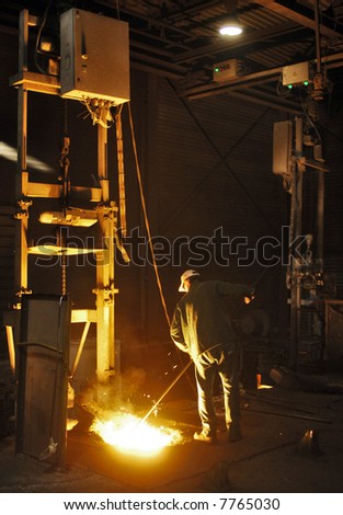 A man working in a cast iron factory close to the melting pit of the foundry