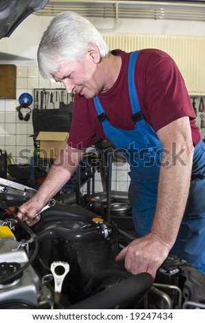 A senior motor mechanic servicing a car inside a garage