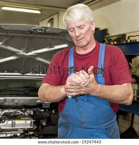 A motor mechanic cleaning his greasy hands after servicing a car. Focus on his hands