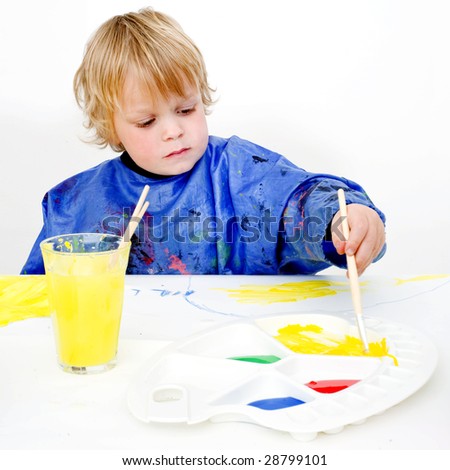 A young painter reaching for the yellow poster paint on his palette