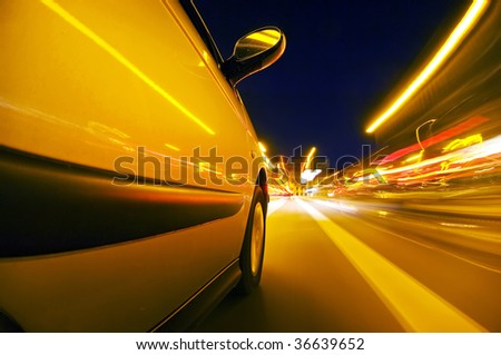 The exterior of a car driving through an urban envrionment, with streaks of light passing by