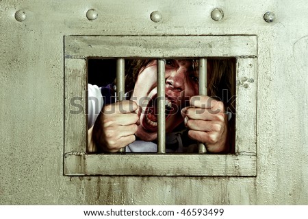 Cross-processed image of a man going insane, grabbing the bars of his jail cell, looking rabid and screaming uncontrollably