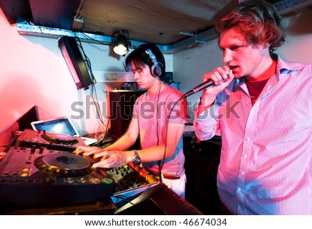 A DJ and a mc in action at a party in a nightclub.
