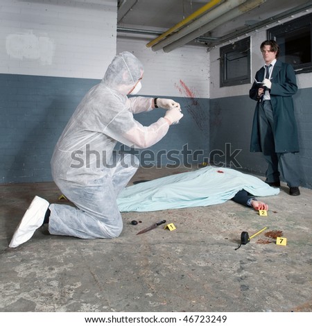 Forensic expert bagging evidence at a crime scene whilst a police inspector is taking notes around the corpse of a murdered businessman