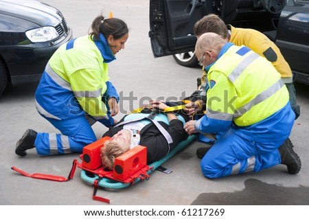 Paramedics and a fireman strapping a wounded woman  with a neck brace on a stretcher
