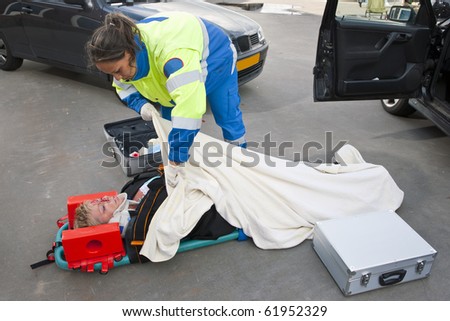 Female paramedic putting a blanket over an injured woman on a stretcher