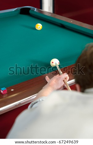 Pool player lining up a shot on the nine ball, with selective focus on hand, cue and cue ball