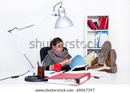 Young woman studying tirelessly, flipping through a folder with her feet on her desk - the background is off-white