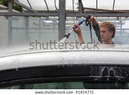 Man washing his car with a high pressure water jet