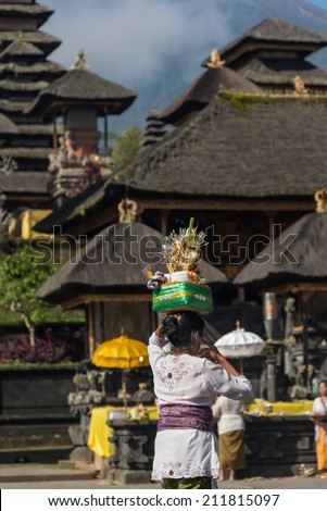 BALI, INDONESIA - AUGUST 17: Balinese woman loads the offering of things in basket on her head for the ceremony at Besakih temple, Bali, Indonesia, on August 17, 2013