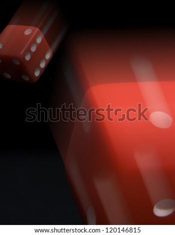 Two red dice ob black background roll by with motion blur
