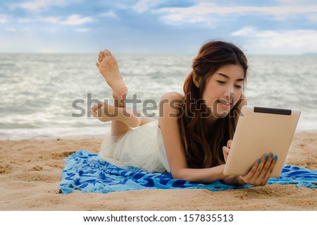asian lady playing tablet on the beach