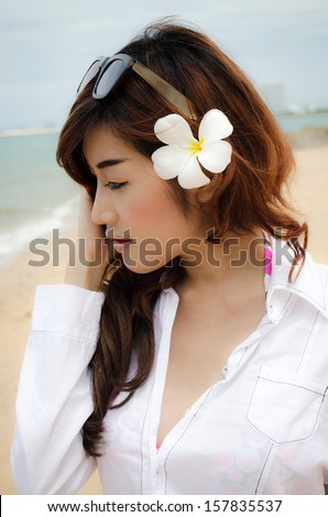 close up shot of a beautiful lady wearing white shirt agianst the beach