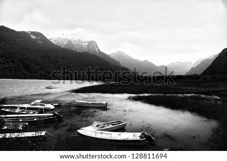 Beautiful black and white lake landscape with some boats in the foreground.