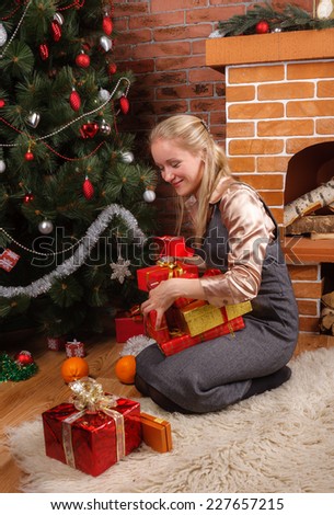 Young beautiful woman in business attire sorting through the presents under the Christmas tree