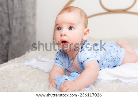 Cute little boy playing with toy on big bed