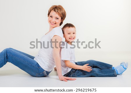 Mother and her son sitting back to back on white background