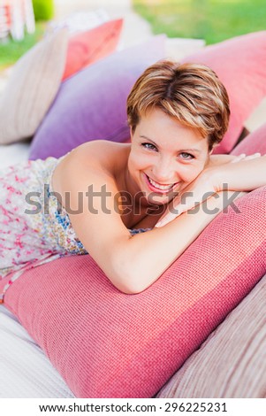 Smiling woman laying on pillows on couch outdoor