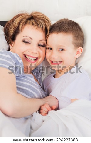 Smiling mother and son laying in bed  in the morning