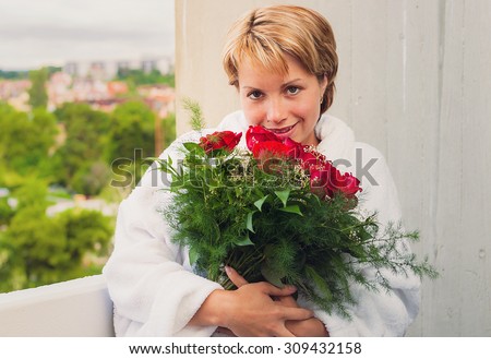 Young beautiful woman with red roses bouquet enjoying her bouquet of red roses
