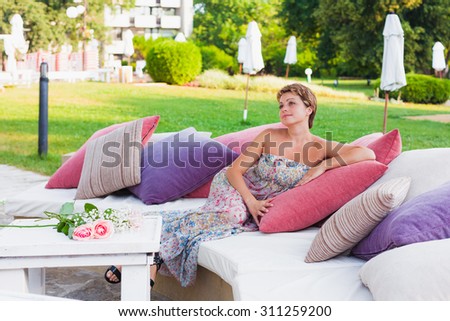 Lovely woman in summer dress sitting on sofa in hotels  bar