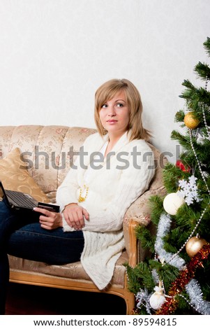 young woman sits with a notebook near Christmas tree