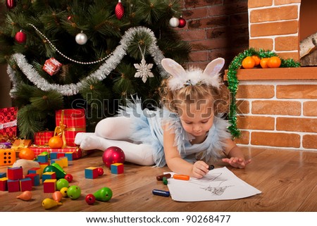 Preaty little girl drawing near Christmas tree