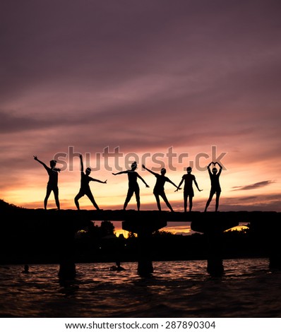 Group of silhouette yoga practicing at sunset on the bridge