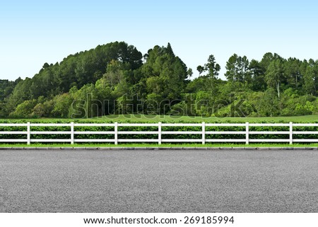 Side view of road, white fence and landscape