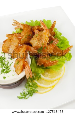 Fried prawns in coconut breading with dipping sauce on a white plate