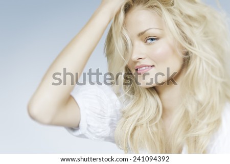 Cheerful looking natural blond woman on light blue background.