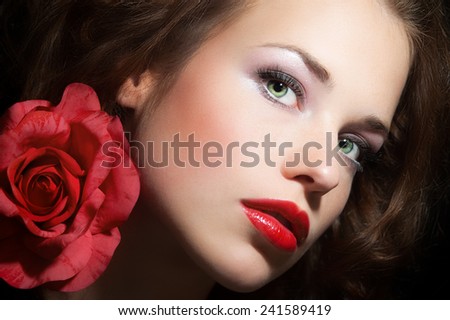 Romantic mysterious portrait of beautiful woman with green eyes and large pink rose. Delicate beauty and fashion concept.