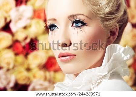 High-key beauty visual with blond model standing on background of roses.