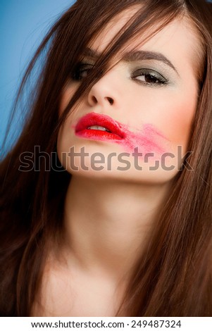 Young woman with bright red lipstick smudged.