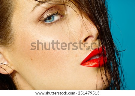 Closeup of a tanned female face with bright coral lipstick.
