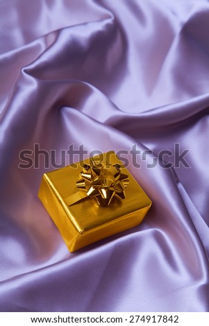 Pretty golden paper gift box on silk sheets.