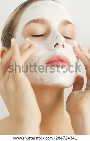 Closeup of beautiful young woman with white clay cosmetic mask. Skincare using masks. White clay clarifying facial mask.