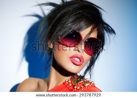 Woman wearing bright red sunglasses, lipstick and dress.