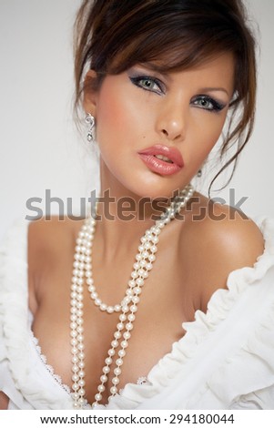 Model with dark hair wearing pearl necklace.