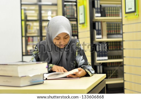 Young Muslim student studying in the library